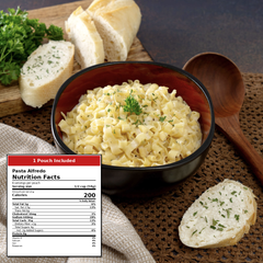 A bowl of creamy pasta Alfredo with bread, parsley, a wooden spoon, and a nutrition label overlay on a rustic tabletop setting.